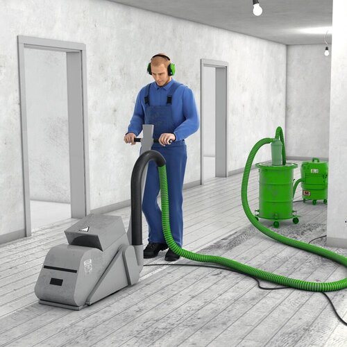 Ein Bauarbeiter mit Kapselgehörschutz schleift einen Boden mit einer Bodenschleifmaschine ab. An die Maschine ist ein Bau-Entstauber angeschlossen, der Staub absaugt.