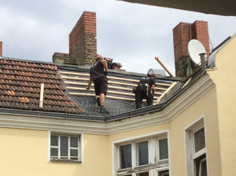 Foto von zwei Dachdeckern, die im Winter auf einem Dach ohne Absturzsicherung arbeiten. – Bildquelle: Nora Michel 
